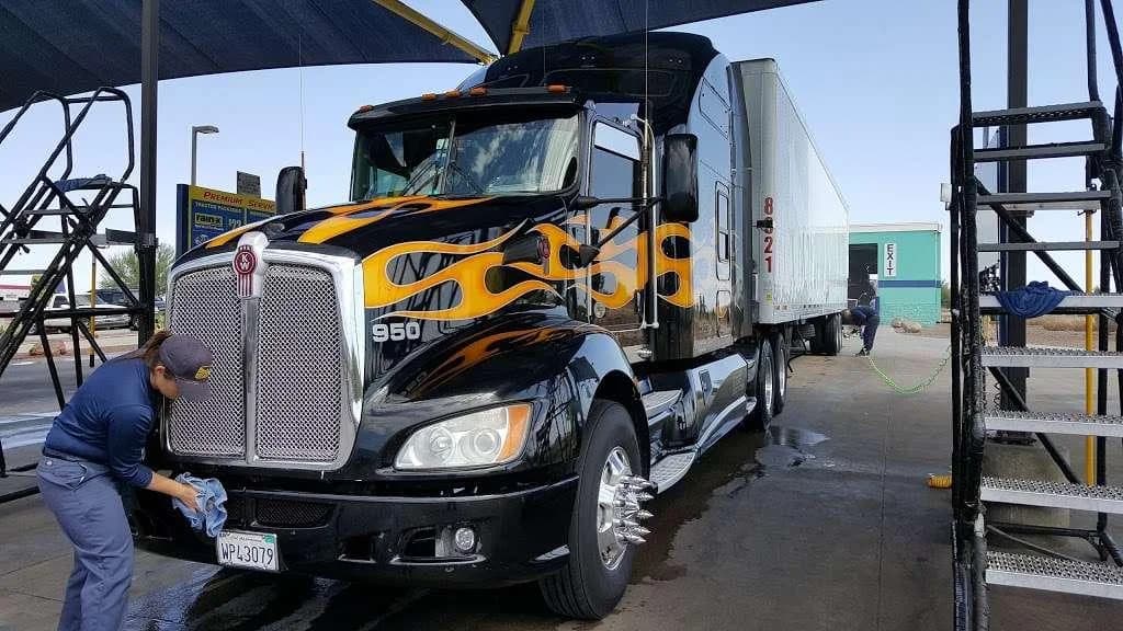 Clean black semi-truck receiving its final finish inspection before departure.